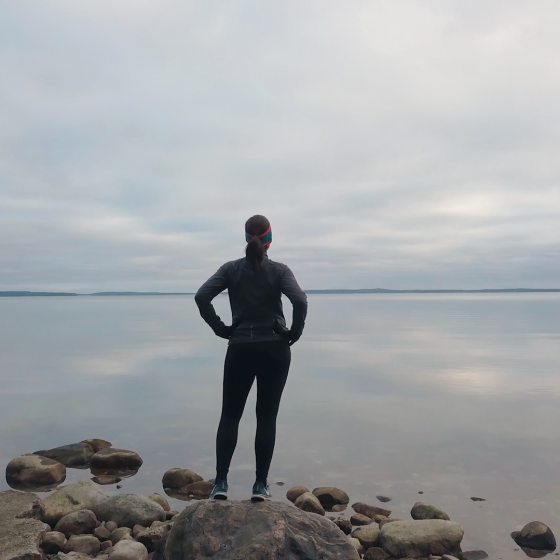 Cecilia Bergroth står utomhus vid vattnet. Cecilia står på en klippa och tittar ut mot havet.