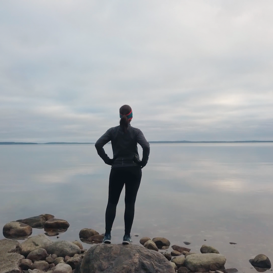 Cecilia står på en klippa och tittar ut mot havet.