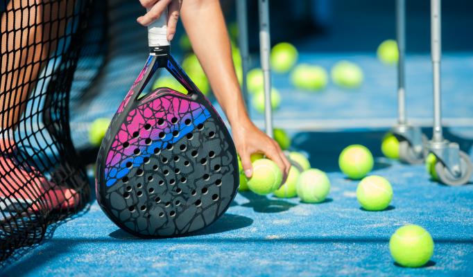 Padelracket och padelbollar på spelplan