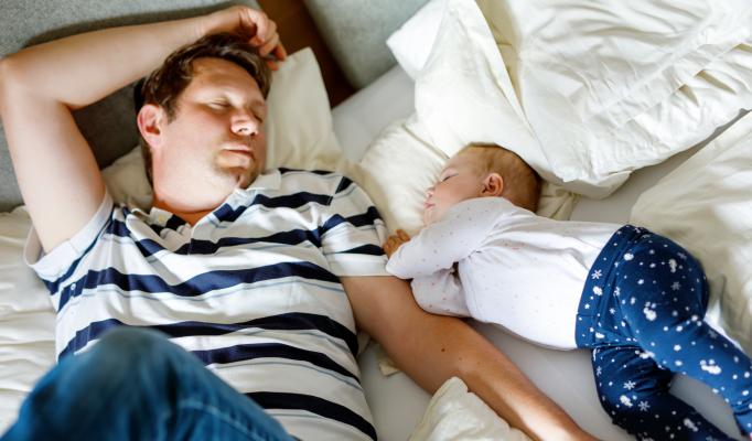 Man som sover bredvid sitt barn