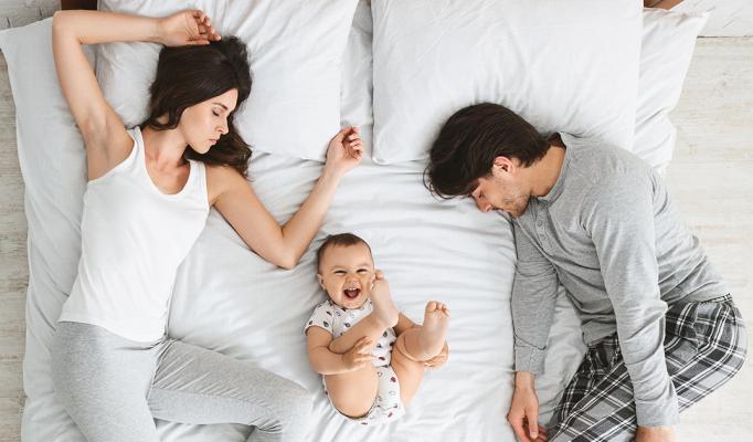 Familj i sängen med skrattande bebis