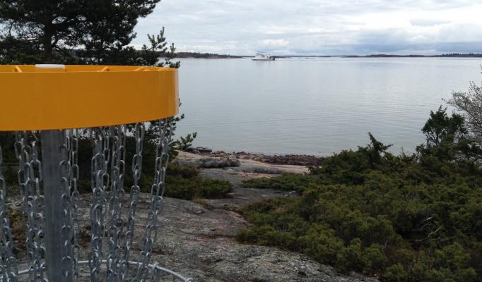 Korg till frisbeegolfbanan ute på Lappo. Skärgårdsfärja i bakgrunden. Korg till frisbeegolfbanan ute på Lappo. Skärgårdsfärja i bakgrunden.