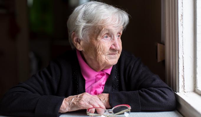 Äldre kvinna sitter vid ett bord Äldre kvinna sitter vid ett bord