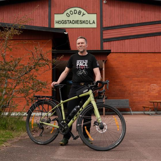 Roger med cykeln framför sitt arbete på Godby Högstadieskola.